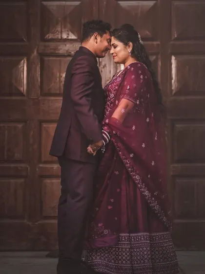 A classic, romantic portrait of the couple. Their foreheads are touching as they stand before a large wooden door, creating a timeless and intimate image.