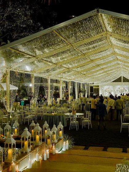 An atmospheric shot of the sangeet venue at night, with guests mingling under the glowing tent. The entire space is transformed into a magical wonderland.