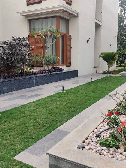 A manicured lawn and garden path at an urban residence. The design uses clean lines and a mix of lawn, pavers, and flower beds to create an elegant and well-organized outdoor space.