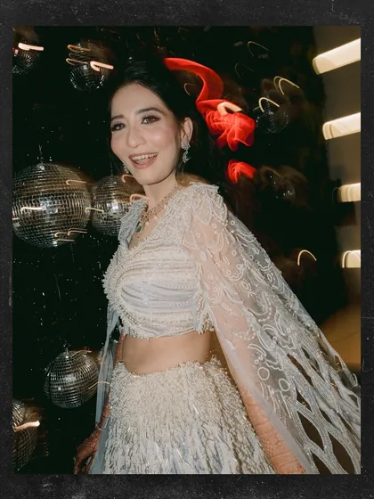 A candid smile from the bride amidst the sangeet madness. Anjali is glowing against the backdrop of disco balls and party lights.