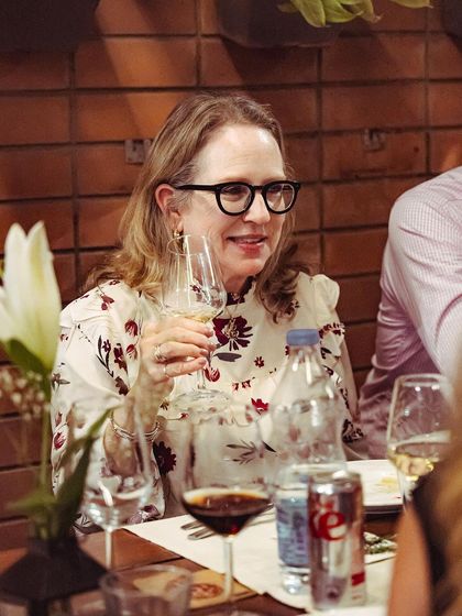 A guest smiling as she enjoys a glass of wine, capturing the happy and relaxed vibe of our events.