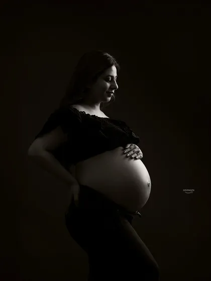 A classic low-key bare-bump profile shot. This style uses dramatic shadows to create a powerful and intimate portrait, focusing on the beautiful curves of pregnancy.