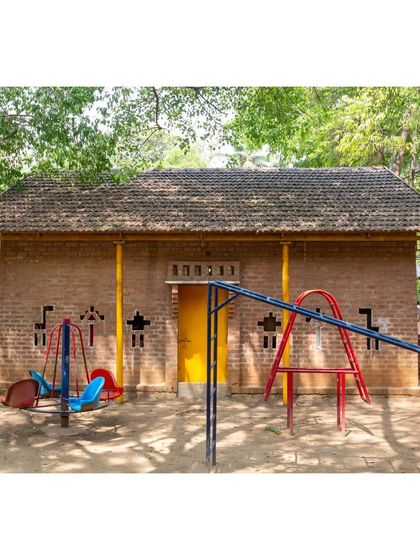 The classroom building seen from its playground. The playful, animal-shaped openings in the brick wall are not just decorative but also provide ventilation and a connection to the outdoors for the children inside.