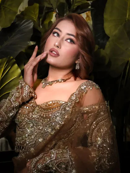 A dramatic and glamorous festive look. The client's hair is styled with soft, voluminous waves that complement her stunning makeup and intricately embroidered outfit.