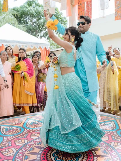 The couple dancing joyfully on a colorful dance floor during their Haldi celebration in Udaipur.