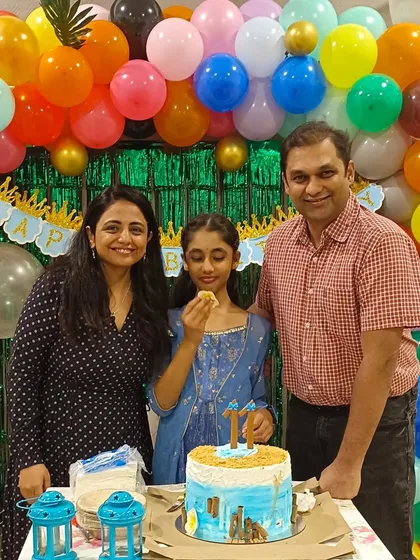 A family enjoying the cake-cutting ceremony at their daughter's 11th birthday party, surrounded by our colorful tropical-themed decor.
