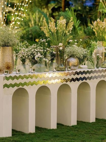 A custom-built bar counter featuring arched details and a chevron-patterned Thikri mirror top. It’s a functional element turned into a piece of art, serving drinks while enhancing the overall aesthetic of the sangeet.