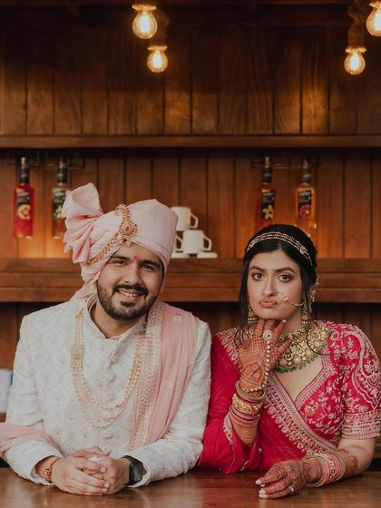 A fun and quirky portrait of the bride and groom at a bar counter. The bride's playful expression and their relaxed pose show a different, more casual side of their wedding day.
