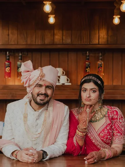 A fun and quirky portrait of the bride and groom at a bar counter. The bride's playful expression and their relaxed pose show a different, more casual side of their wedding day.
