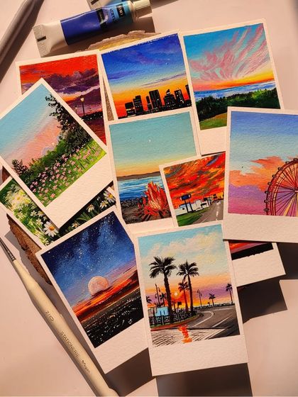 A beautiful spread of my custom-painted polaroids, showcasing a variety of colorful landscapes and sunset scenes.