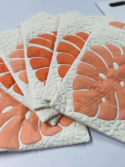 A fanned-out display of the monstera cushion covers, highlighting the beautiful appliqué and stipple quilting.