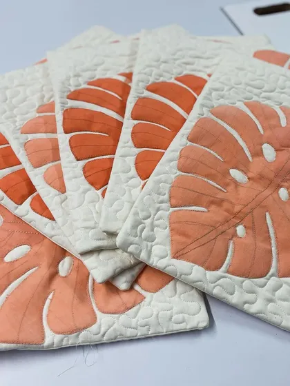 A fanned-out display of the monstera cushion covers, highlighting the beautiful appliqué and stipple quilting.