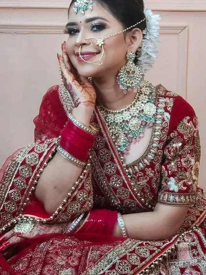 A close-up of a bride wearing a traditional red lehenga with a beautiful Kundan and mint-green stone jewellery set. The smile says it all.