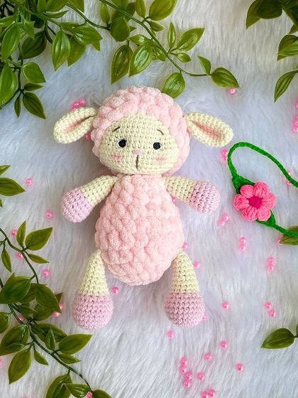A sweet pink lamb made with a mix of regular and fluffy yarn for a lovely texture. She comes with a removable flower headband.