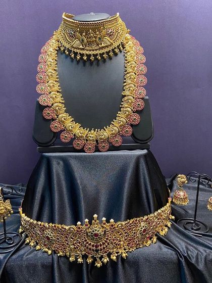 This full bridal set is crafted with beautiful kemp stones in a classic design. It includes a choker, long necklace, earrings, maang tikka, and a matching vaddanam for a complete, cohesive look.