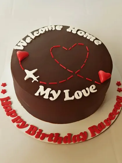 A sweet and simple "Welcome Home" cake. The chocolate cake is decorated with a plane's flight path creating a heart, perfect for celebrating the return of a loved one.