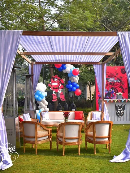 A comfortable seating cabana at the Transformers party, with a themed backdrop and balloon arrangement.