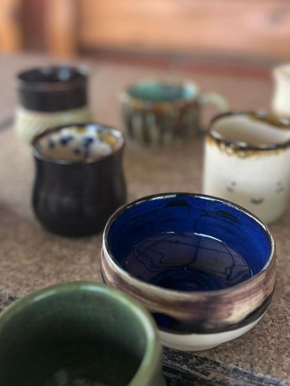 A collection of finished pieces from a beginner's course, showcasing a variety of shapes, sizes, and glaze colors.