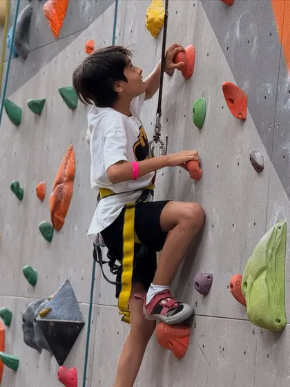 Geared up and ready to go! This young climber is focused on his route, learning problem-solving skills and coordination with every move.