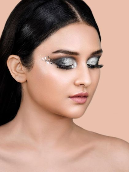A close-up beauty shot showcasing a dramatic silver eye makeup look with crystal embellishments. This type of detailed work is ideal for makeup artists' portfolios and cosmetic campaigns.