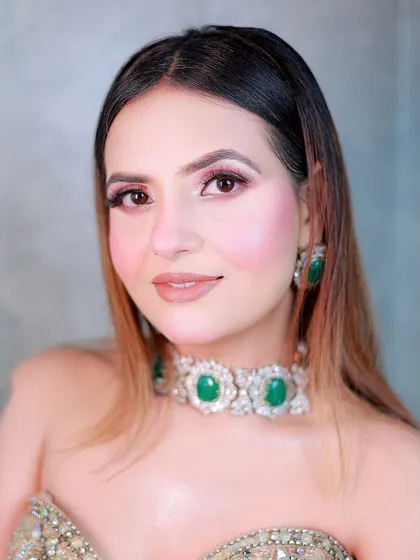 A close-up beauty shot focusing on the soft makeup and the stunning emerald and diamond choker.