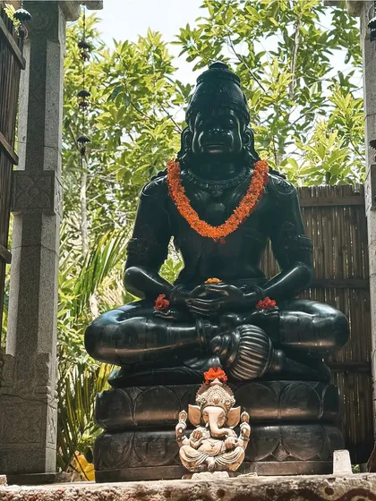 A statue of Hanuman, adorned with a flower garland. The deities and sacred art around the ashram create an atmosphere of devotion and spiritual inspiration.