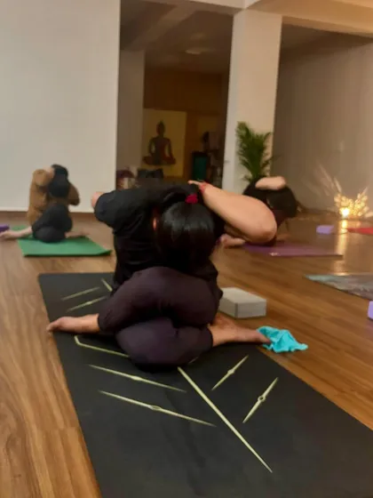 A student in a variation of a deep hip-opening posture, working towards Yoganidrasana (Yogic Sleep Pose). This requires immense patience and consistent practice.