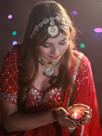 This shot shows the model looking down at the diya, creating a moment of quiet introspection. The warm light from the flame illuminates her face beautifully.