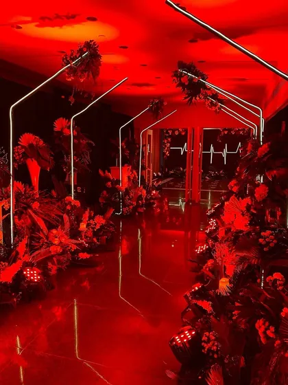 A dramatic, futuristic entrance for a cocktail party, using red lighting and neon arches to create a high-impact tunnel effect.