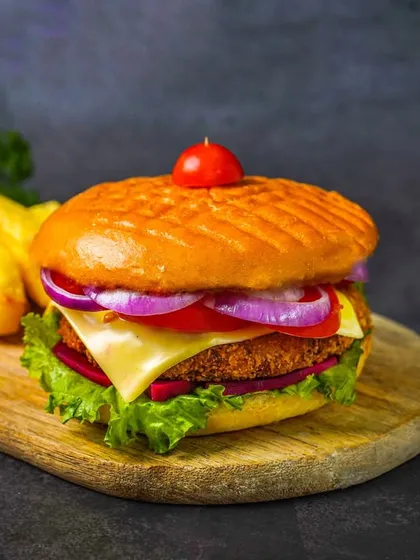 A classic, juicy burger served on a wooden board with a side of thick-cut fries. The dark, textured background and focused lighting create an irresistible, high-impact image for any cafe or restaurant menu.