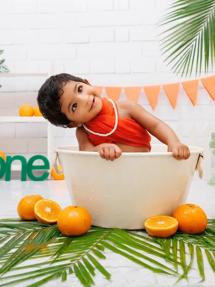 A cute and playful pose from a baby girl in her orange-themed tub splash session.