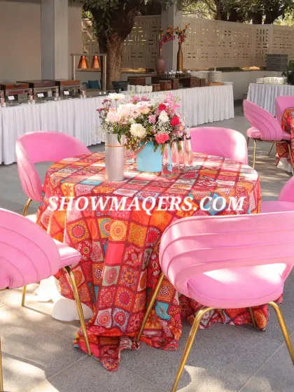 Chic guest seating with modern pink chairs and tables covered in colorful patterned linen, perfect for a stylish poolside Haldi.