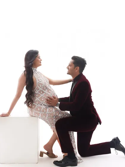 A sweet and chivalrous moment. The father-to-be kneels to connect with the baby bump, creating a romantic and heartwarming image.
