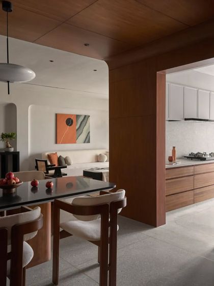 This view from the dining table looks towards the kitchen, emphasizing the open and connected layout. Natural light and a mix of textures create a dynamic interplay that evolves throughout the day.