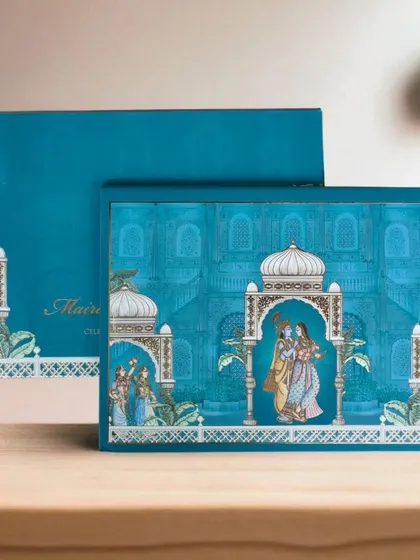 I love bringing traditional art forms to life, like in this Pichwai-themed invitation box. The vibrant teal and intricate illustrations of Radha and Krishna create a piece that is both culturally rich and modern in its presentation.