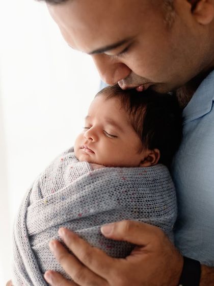 A father's gentle kiss on his sleeping baby's head. This is a simple, powerful expression of love and protection.