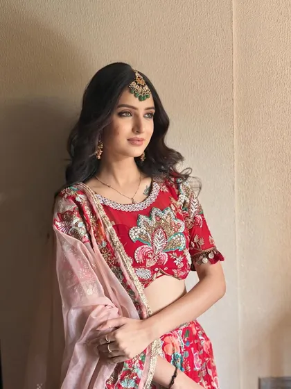 A classic festive look in a red embroidered lehenga. The makeup is soft and elegant, with a green maang tikka adding a beautiful contrast.