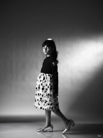 A walking pose that shows confidence and movement. This black and white shot is great for a portfolio as it demonstrates her comfort in front of the camera and her natural sense of style.