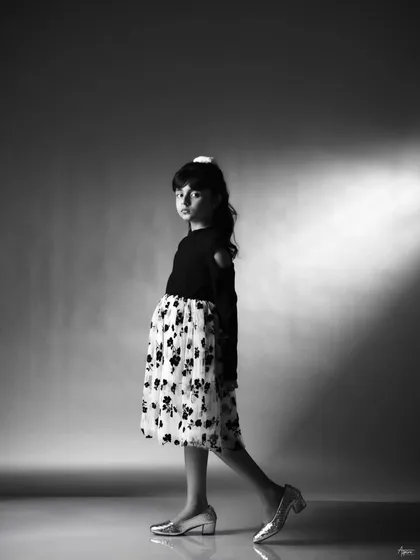 A walking pose that shows confidence and movement. This black and white shot is great for a portfolio as it demonstrates her comfort in front of the camera and her natural sense of style.