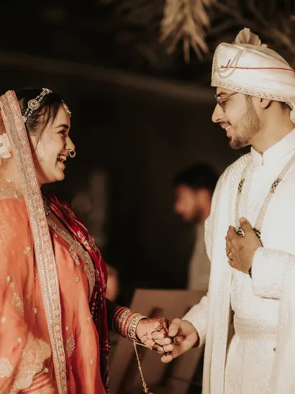 A quiet, candid moment of connection. The bride and groom share a laugh and a gentle touch, a small, authentic interaction that speaks volumes about their relationship.