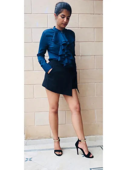 Style is your secret weapon to stand and deliver in a competitive world. This look, featuring a structured ruffle shirt and an asymmetrical skort, creates a powerful silhouette that is both professional and chic.