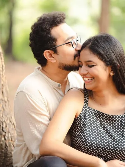 A warm, color portrait of Soham giving Anjum a gentle kiss on the forehead. The natural setting and their relaxed expressions make this a sweet and timeless image.