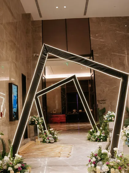 We design modern and futuristic entrances that make a bold statement. This geometric tunnel, outlined with clean LED lighting and flanked by soft white florals, offers a contemporary and stylish welcome for any evening event.