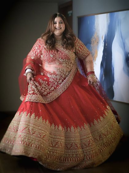 My beautiful bride Forum, looking like a dream in her red and gold lehenga. The makeup is classic and timeless, with soft curls framing her face.