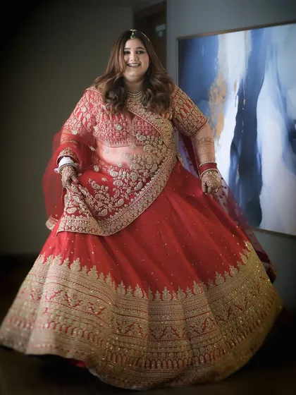 My beautiful bride Forum, looking like a dream in her red and gold lehenga. The makeup is classic and timeless, with soft curls framing her face.