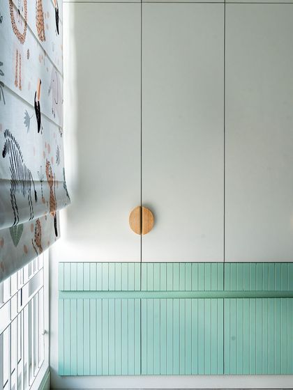 The wardrobe in the kids' room is painted a soft green with fluted details and round wooden handles, continuing the home's earthy and modern farmhouse theme.
