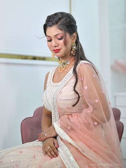 A behind-the-scenes shot of a model in a delicate white chikankari lehenga with a peach-colored choker set.