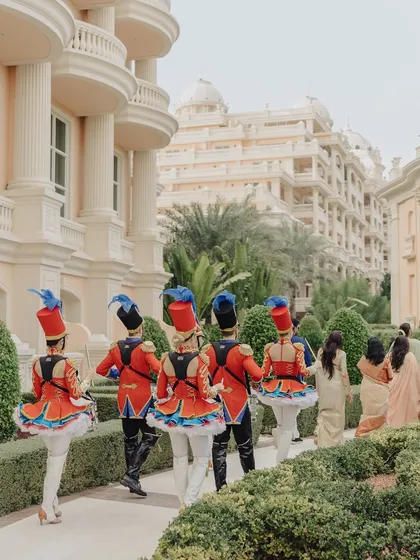 A rear view of the colorful marching band performers, showcasing their unique costumes as they lead the way through the venue's gardens.