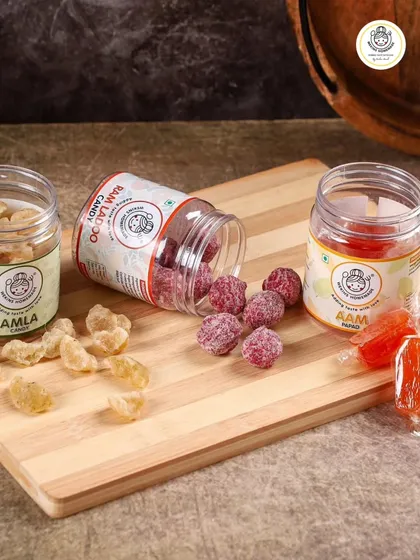 A delightful spread of our sweet and sour treats. This image showcases our healthy Amla Candy, flavorful Ram Ladoo Candy, and the ever-popular Orange Aam Papad.