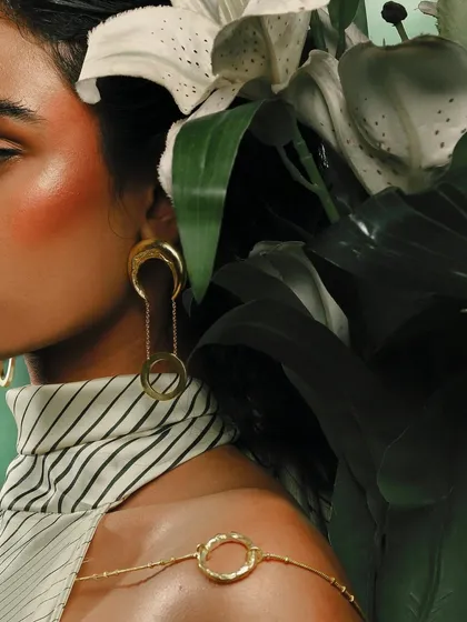 A detailed close-up of the earrings and body chain from the Batoki Art campaign. This angle highlights the craftsmanship and unique design of the jewelry pieces.